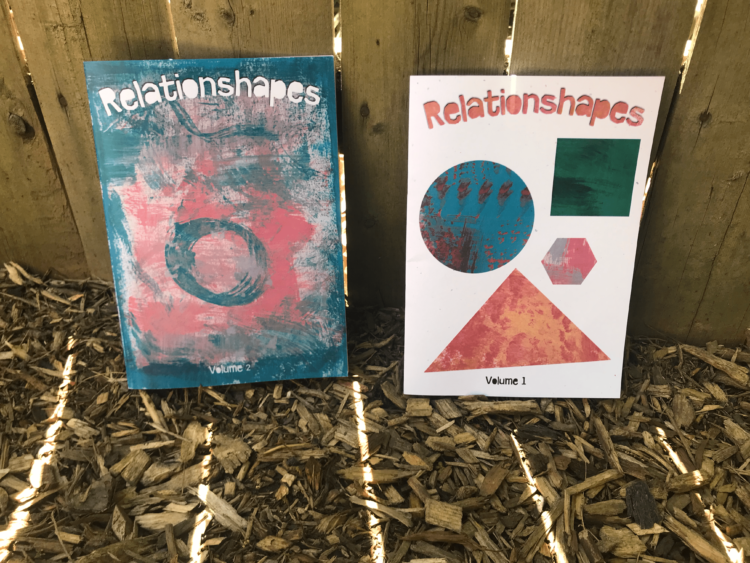 Two brightly colored zines lean against a fence post, each a volume of "Relationshapes"